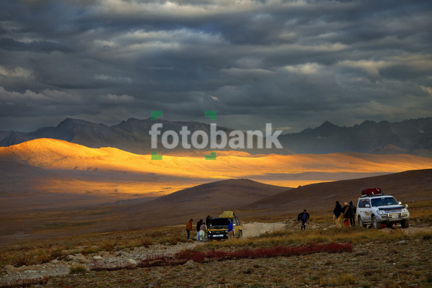 Travelers Enjoying in the open Fields in the Mountains with Jeeps Beautiful Landscape Mountains with Clouds in the Evening