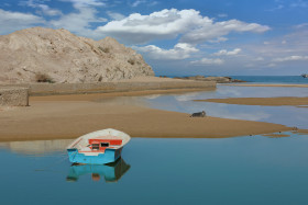 A Boat Waiting on the Shore of Blue Sea with Clear Weather Beautiful Clouds in the sky