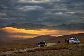 Travelers Enjoying in the open Fields in the Mountains with Jeeps Beautiful Landscape Mountains with Clouds in the Evening